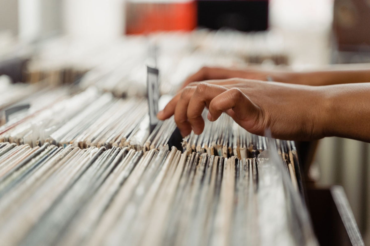 A hand browsing through vinyl records in a record shop